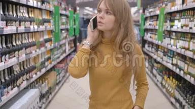 可爱的女人用<strong>手机</strong>说话，决定在<strong>超市</strong>买什么酒